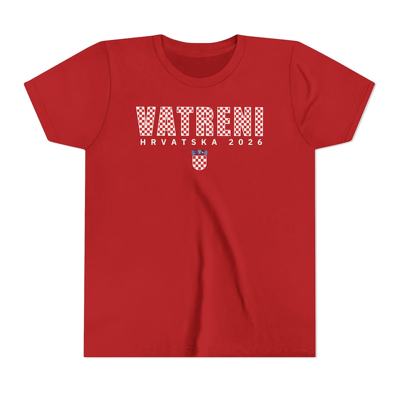 May include: A red t-shirt with the word "VATRENI" in white checkered letters. Below the word is "HRVATSKA 2026" in white letters, and a Croatian coat of arms. The shirt is made of a soft material.