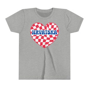 Puede incluir: Una camiseta gris con un dise&ntilde;o de coraz&oacute;n a cuadros rojos y blancos. El coraz&oacute;n tiene la palabra "HRVATSKA" escrita en letras azules.