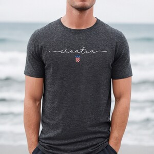 May include: A dark gray t-shirt with the word "croatia" written in white script across the chest. The Croatian coat of arms is centered below the word.