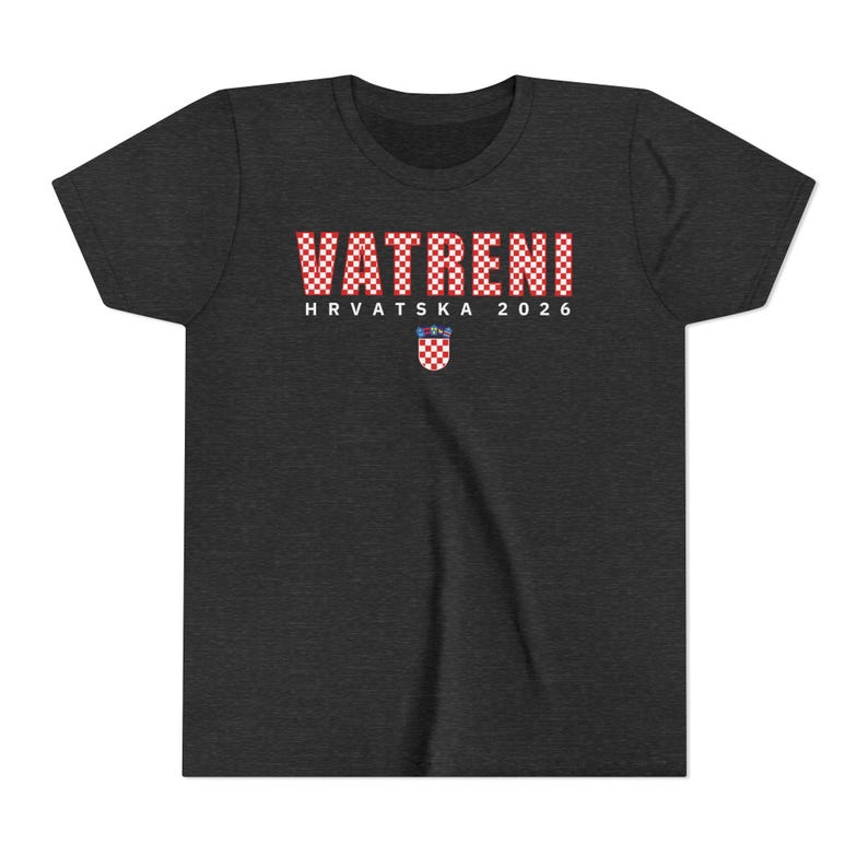 May include: Dark gray t-shirt with the word "VATRENI" in a red and white checkered pattern. Below the word is "HRVATSKA 2026" and a Croatian coat of arms. The shirt is made of a soft material.