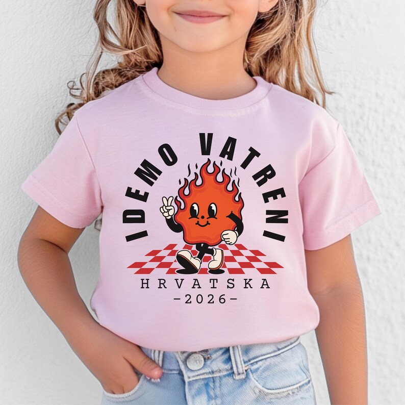 May include: A light pink t-shirt featuring a cartoon flame character with the text "IDEMO VATRENI" and "HRVATSKA - 2026-". The flame is on a red and white checkered pattern.
