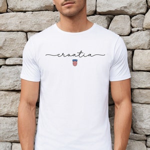 May include: White t-shirt with the word "croatia" written in cursive script and a small red and white checkered Croatian coat of arms below it.