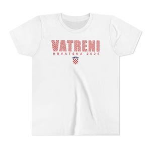 May include: White t-shirt with the word "VATRENI" in red and white checkered letters. Below the word is "HRVATSKA 2026" in red letters, and a Croatian coat of arms. The shirt has short sleeves and a crew neck.