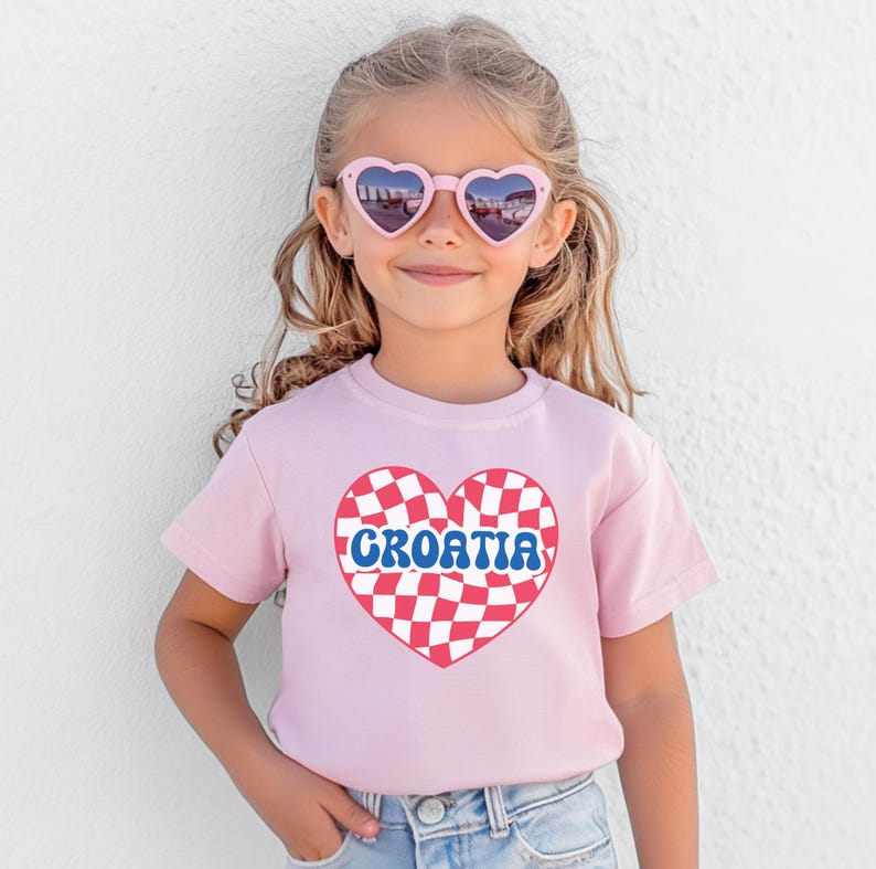 May include: A pink t-shirt with a red and white checkered heart that says "CROATIA" in blue letters.