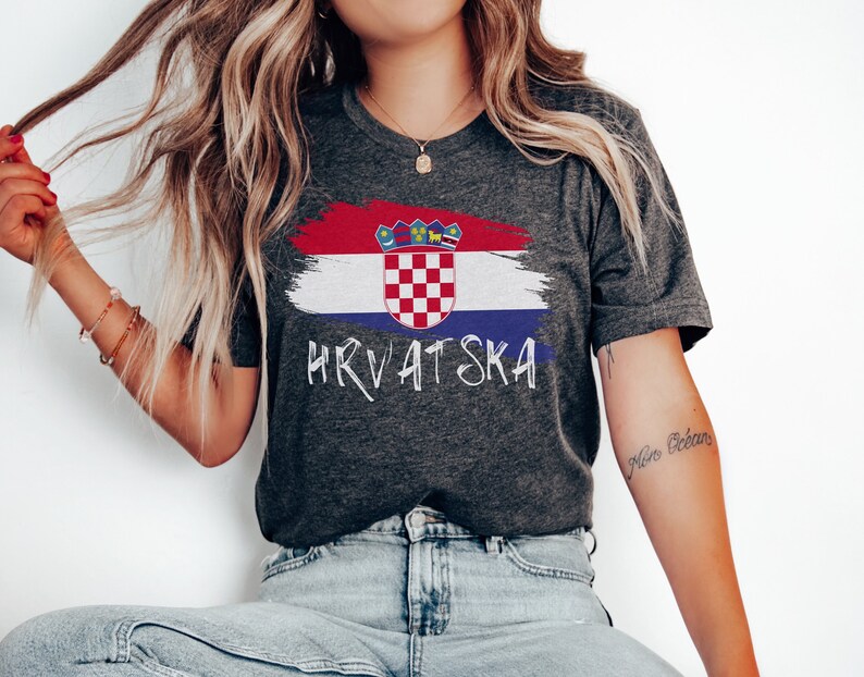 May include: A dark grey t-shirt featuring a white paint-splattered Croatian flag design and the word "HRVATSKA" in white lettering.