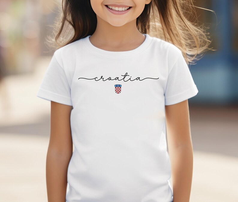 May include: White t-shirt with the word "croatia" written in cursive and the Croatian coat of arms in the center.
