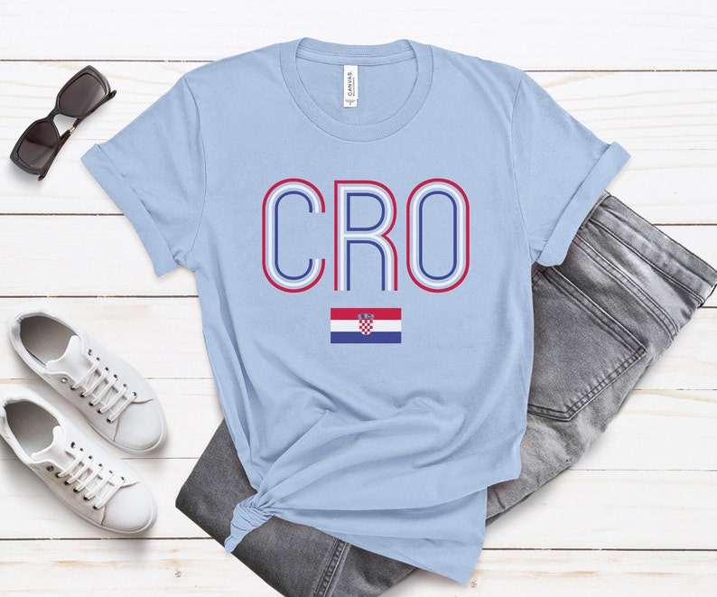 May include: Light blue t-shirt with the word "CRO" in red, white, and blue outlined letters. The Croatian flag is below the word.