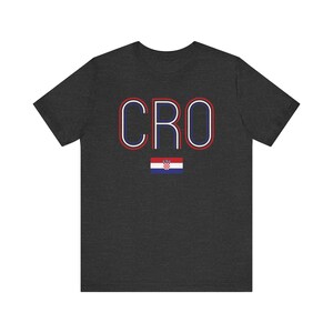 May include: A dark gray t-shirt with the word "CRO" in red, white, and blue outlined letters. A small Croatian flag is below the text.