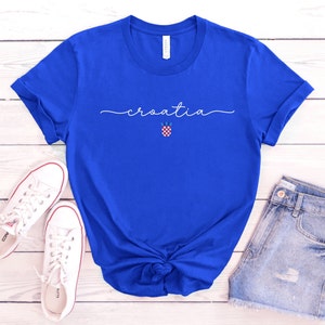 May include: A royal blue t-shirt with the word "croatia" written in white cursive script. A small Croatian flag is centered below the word.