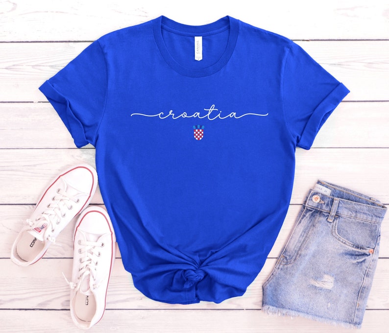 May include: A royal blue t-shirt with the word "croatia" written in white cursive script. A small Croatian flag is centered below the word.