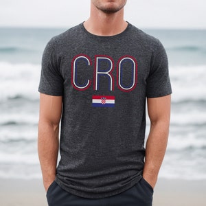May include: A dark gray t-shirt with the word "CRO" in white outlined in red and blue. A small Croatian flag is below the word.