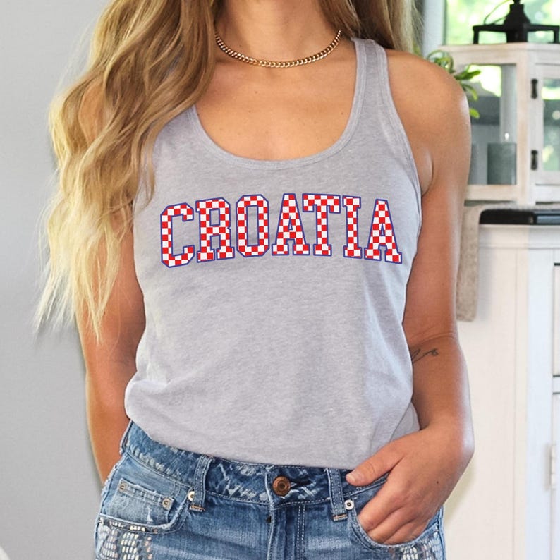 May include: A gray tank top with the word "CROATIA" printed across the front in red and white checkered letters. The tank top is sleeveless and made of a soft material. The person is wearing blue denim shorts.