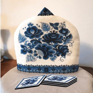 May include: White teapot cozy with a blue floral design. The cozy has a blue and white trim. Four blue and white coasters are stacked next to the cozy.