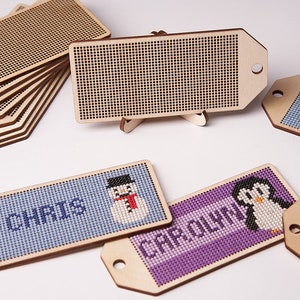 K&ouml;nnte beinhalten: Ein Satz aus Holz-Weihnachtsbaumschmuck-Etiketten mit verschiedenen Designs. Die Etiketten sind leer und k&ouml;nnen mit Namen oder Nachrichten personalisiert werden. Die Designs beinhalten einen Schneemann, einen Pinguin, eine Schneeflocke und einen Gnom. Die Etiketten sind aus Naturholz gefertigt und haben einen rustikalen Look.