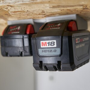 May include: Two black and red Milwaukee M18 HD12.0 high output lithium-ion batteries mounted on a wooden surface.