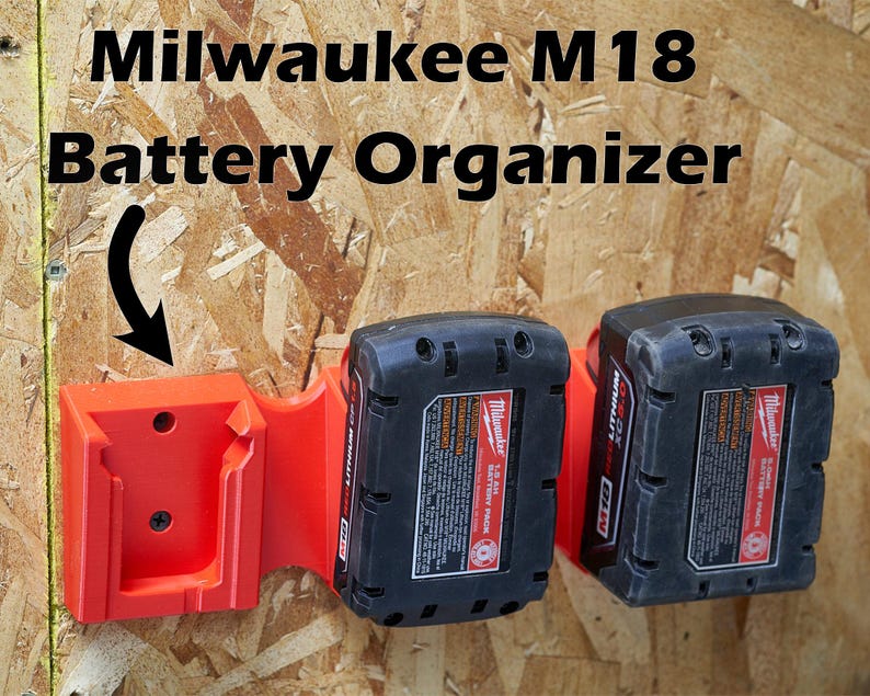 May include: Red plastic wall mount organizer for two Milwaukee M18 batteries. The organizer is mounted to a wood surface.