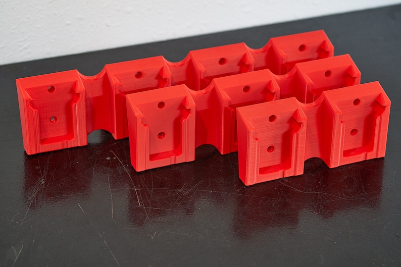 May include: Five red plastic wall mounts with a rectangular shape and a U-shaped cutout. The mounts have small holes for screws.