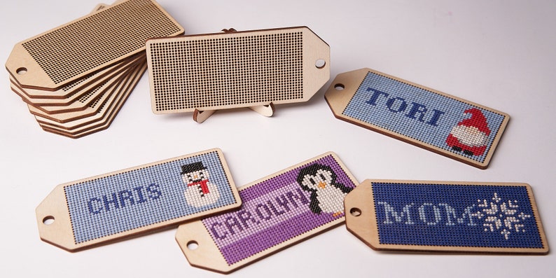 K&ouml;nnte beinhalten: Ein Satz aus Holz-Weihnachtsbaumschmuck-Etiketten mit verschiedenen Designs. Die Etiketten sind leer und k&ouml;nnen mit Namen oder Nachrichten personalisiert werden. Die Designs beinhalten einen Schneemann, einen Pinguin, eine Schneeflocke und einen Gnom. Die Etiketten sind aus Naturholz gefertigt und haben einen rustikalen Look.