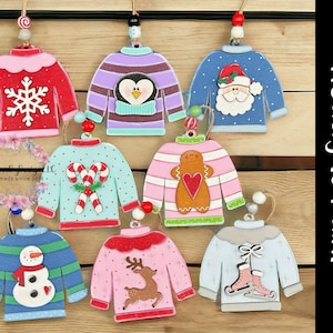 May include: Set of eight unfinished wooden Christmas ornaments shaped like sweaters. Each ornament features a different design, including a snowflake, penguin, Santa Claus, candy canes, gingerbread man, reindeer, snowman, and ice skates. The ornaments are ready to be painted.
