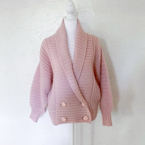 light orchid pink, chunky knit double breasted sweater. ribbed and has double set of light pink large circle buttons.