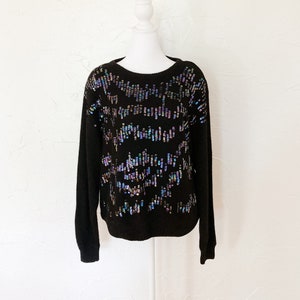 black fuzzy sweater with iridescent blue, green, pink, purple cascading sequins down the front and across shoulders.