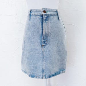 May include: Light blue denim skirt with a classic five-pocket design. The skirt has a button and zipper closure, belt loops, and a slightly faded wash. The skirt is displayed on a white mannequin against a white background.