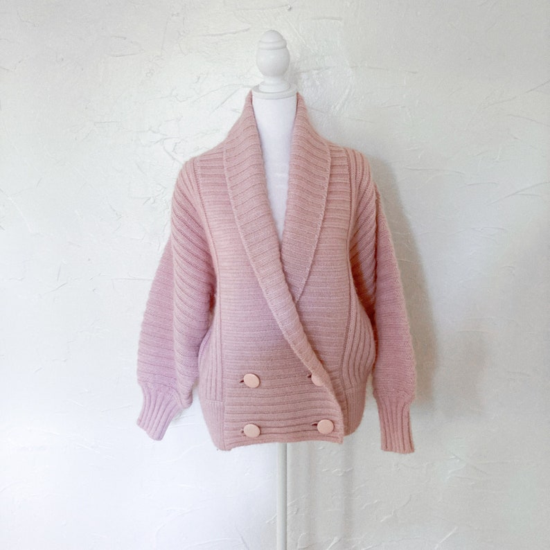 light orchid pink, chunky knit double breasted sweater. ribbed and has double set of light pink large circle buttons.