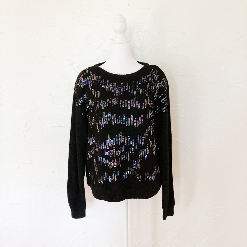 black fuzzy sweater with iridescent blue, green, pink, purple cascading sequins down the front and across shoulders.
