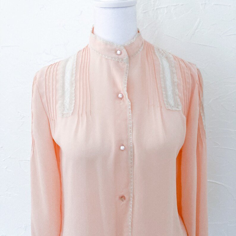 light peachy pink button up blouse with mock collar, and cream lace accents