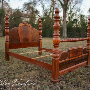 May include: A vintage wooden bed frame with a carved headboard and footboard. The bed frame is in a rustic setting, with grass and trees in the background.