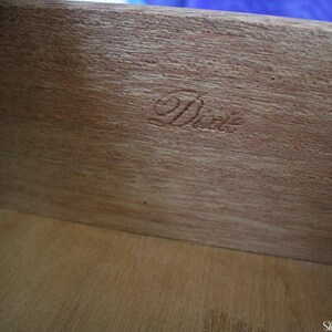 May include: Close-up of a wooden drawer interior with the word "Dixie" stamped in the wood.