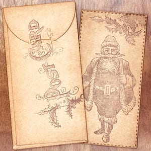May include: Two vintage-style Christmas cards on a wooden surface. One card is an envelope with the word "Christmas" printed vertically. The other card features a detailed illustration of Santa Claus and holly.