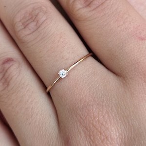 Puede incluir: Un delicado anillo de oro con un pequeño diamante engastado en el centro.