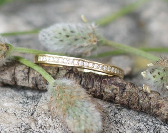 May include: A thin gold band with a row of small diamonds set in a channel setting.