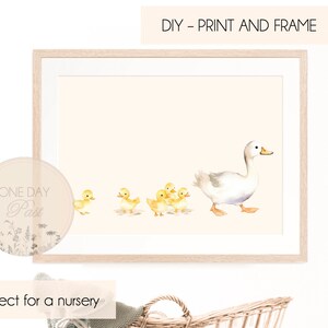 May include: A watercolour illustration of a white duck leading a line of yellow ducklings. The ducks are walking on a pale pink background. The image is framed in a light wood frame. The text "DIY - PRINT AND FRAME" is at the top of the image. The text "Perfect for a nursery" is at the bottom of the image.