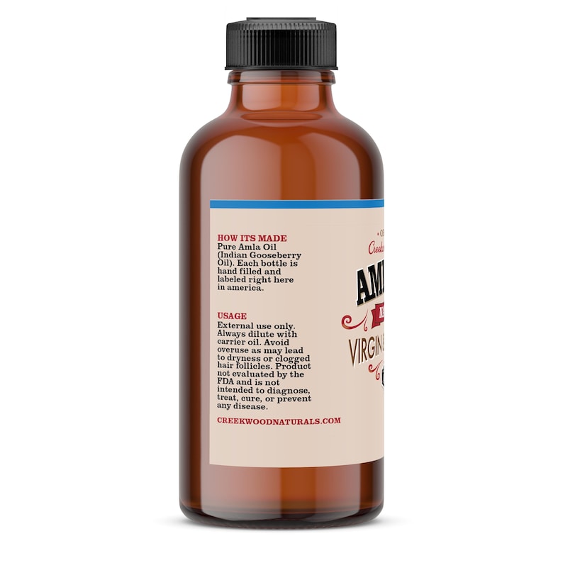 May include: A brown glass bottle with a blue label that reads "Pure Amla Oil (Indian Gooseberry Oil)". The label also includes instructions on how to use the oil and a website address: CREEKWOODNATURALS.COM.