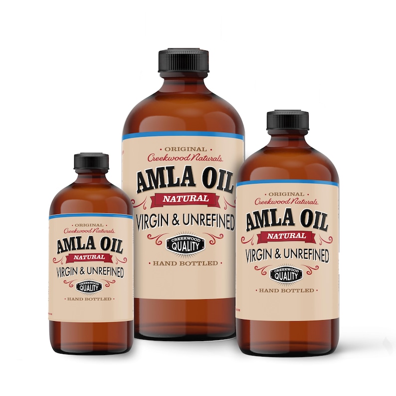 May include: Three amber glass bottles of Amla Oil, labeled "Original Creekwood Naturals Amla Oil Natural Virgin & Unrefined" with a hand-drawn logo and the text "Creekwood Quality" in a black circle. The bottles are of different sizes and are arranged from largest to smallest.