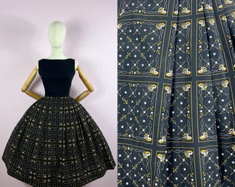May include: A vintage black dress with a scoop neckline and a full skirt. The skirt features a repeating pattern of squares with white stars, yellow anchors, and rope designs. The dress is displayed on a mannequin.
