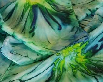May include: A blue and green silk scarf with a swirling, abstract pattern. The scarf is made of a soft, flowing fabric and has a delicate, hand-painted design.
