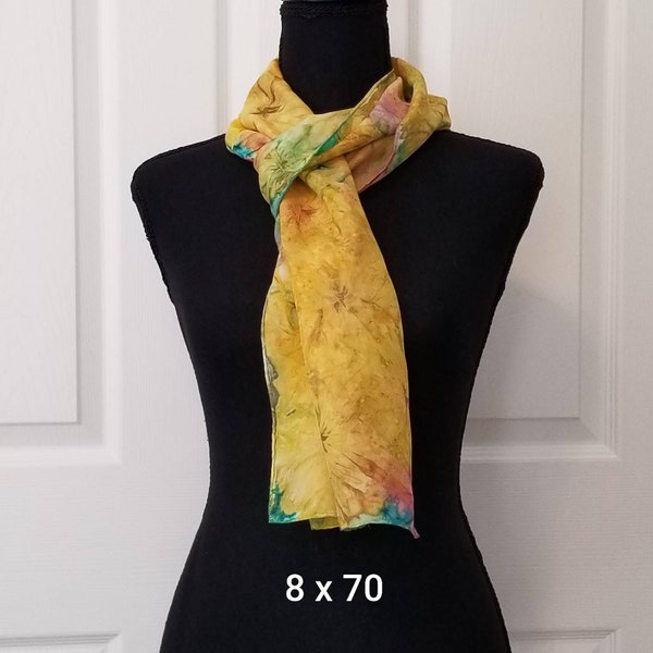 May include: A yellow silk scarf with a floral pattern and teal accents. The scarf is 8 inches wide and 70 inches long.