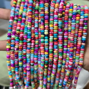 May include: A collection of colorful beaded necklaces. The beads are small and round, in a variety of colors including red, blue, green, yellow, and purple. The necklaces are held together with white tassels at the bottom. The beads are strung together in a vertical pattern.