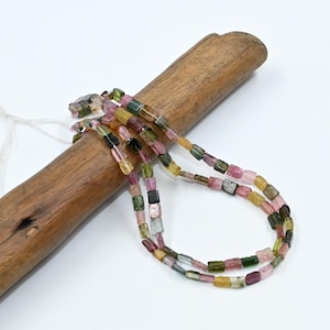 Può includere: Un filo di perline di tormalina quadrate multicolori. Le perline sono un mix di rosa, verde, nero e giallo.