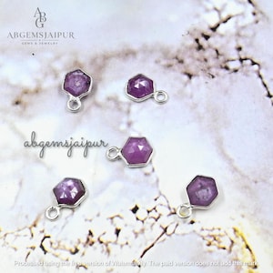 May include: Five small, hexagonal-shaped charms featuring faceted, deep pinkish-purple gemstones set in silver-toned metal frames. Each charm includes a small circular jump ring at the top for attachment, arranged in a scattered pattern.