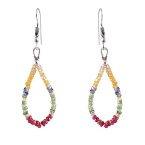 May include: A pair of dangle earrings with a teardrop shape. The earrings are made of silver and feature a multi-colored gemstone bead design. The beads are arranged in a rainbow pattern, starting with yellow, then orange, red, green, blue, and purple.