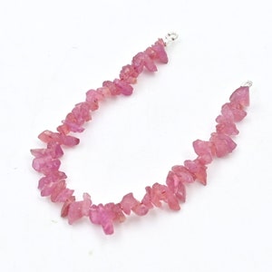 Può includere: Una collana di pietre preziose rosa con chiusure argentate. La collana è realizzata con piccole pietre preziose rosa di forma irregolare.