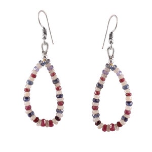 Peut inclure: Une paire de boucles d'oreilles pendantes composées d'un anneau en forme de goutte, orné de petites perles à facettes dans des tons bleu profond, rouge rubis et blanc translucide. Les perles sont montées sur une structure métallique argentée.