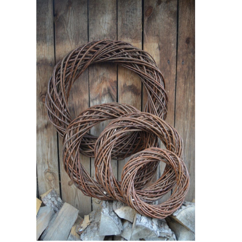May include: Three brown wicker wreaths of varying sizes, nested together. The wreaths are made of natural materials and have a rustic appearance.