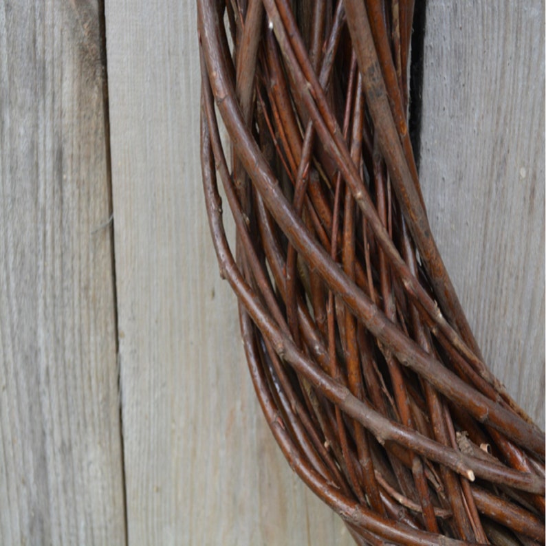 May include: A brown twig wreath, woven in a circular shape. The wreath is made of natural twigs and is perfect for decorating a door or wall.