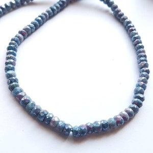Könnte beinhalten: Eine Strähne blauer facettierter Edelsteinperlen. Die Perlen sind klein und rund und haben einen leicht schillernden Glanz.