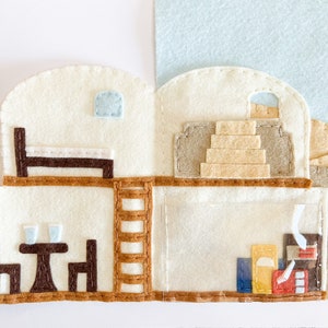 May include: A felt playhouse with two levels, a bed, a table and chairs, a ladder, and a staircase. The playhouse is decorated with brown, beige, and white felt.